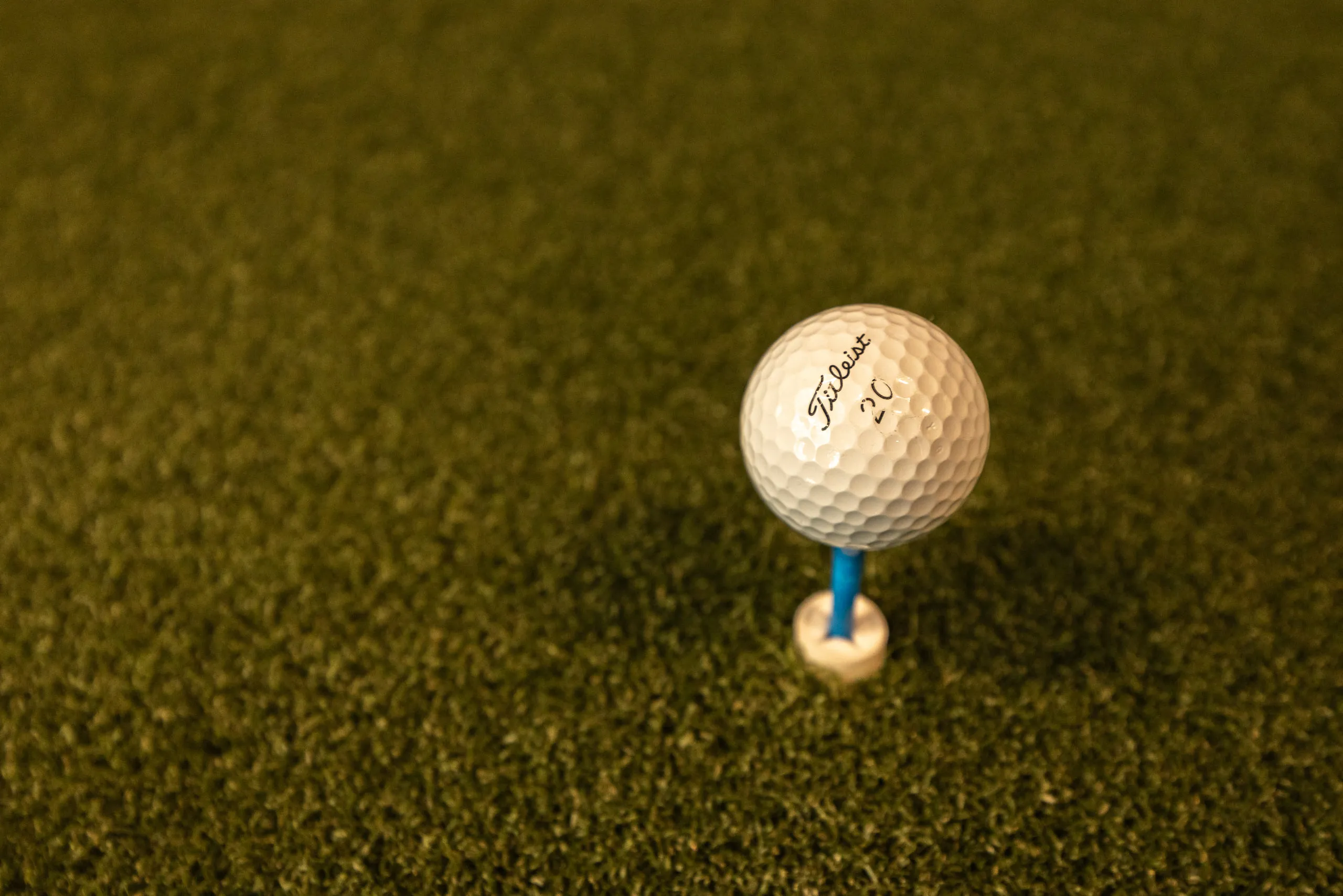 A golf ball on a tee on the hitting turf at All Square.
