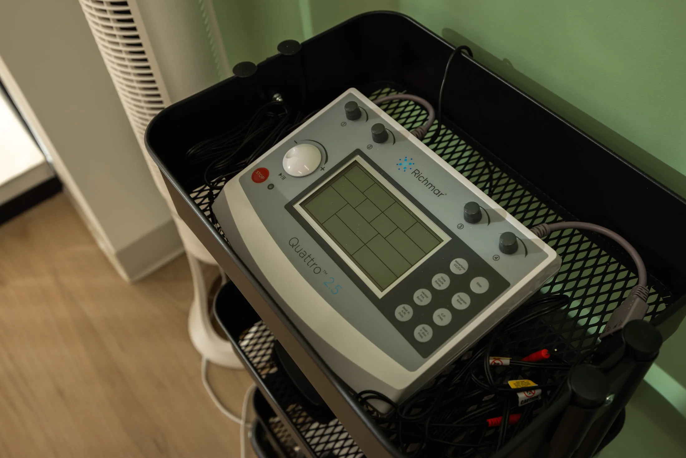 An electrical stimulation unit on a mobile cart in a treatment room.