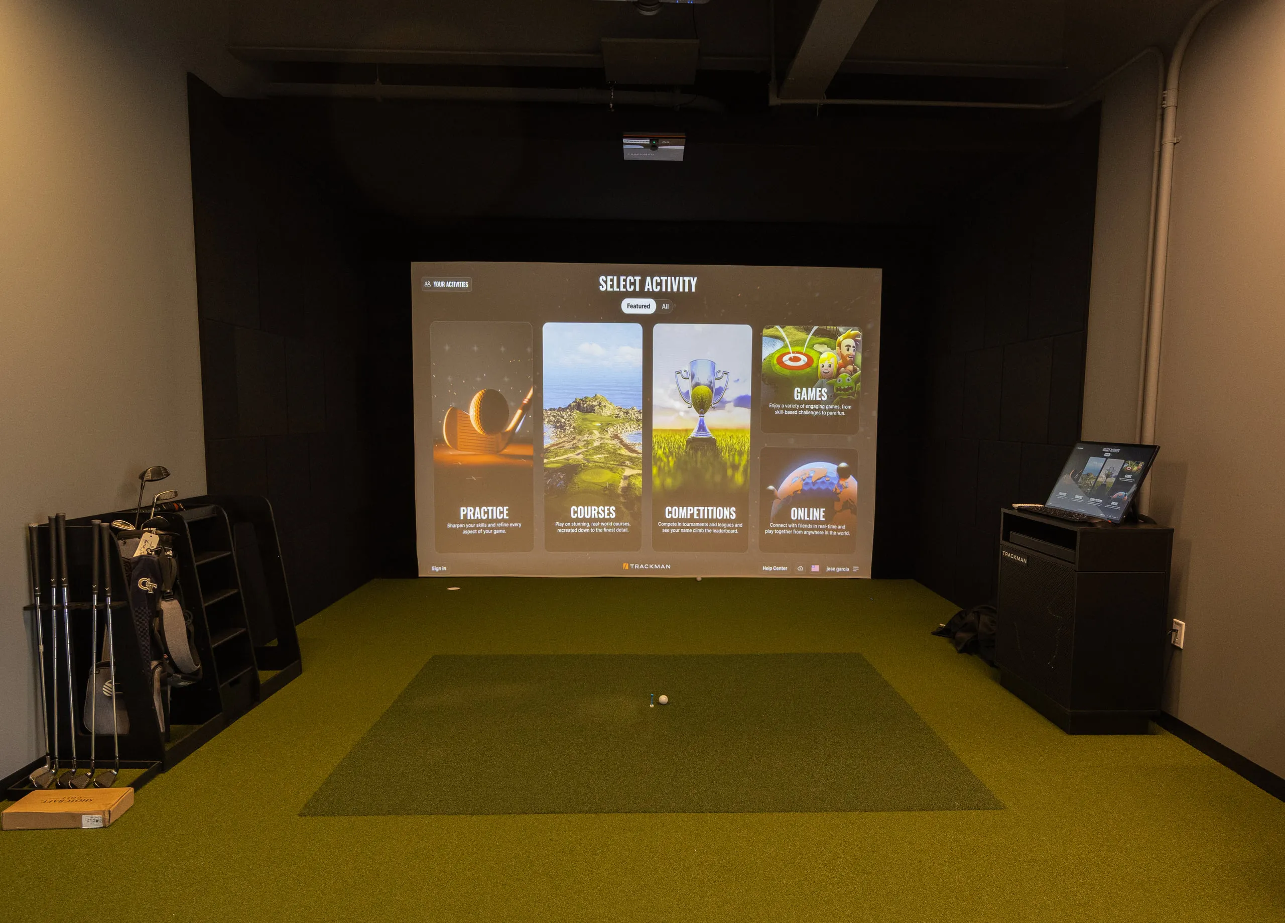 A TrackMan simulator bay at All Square with the projection screen and hitting turf.