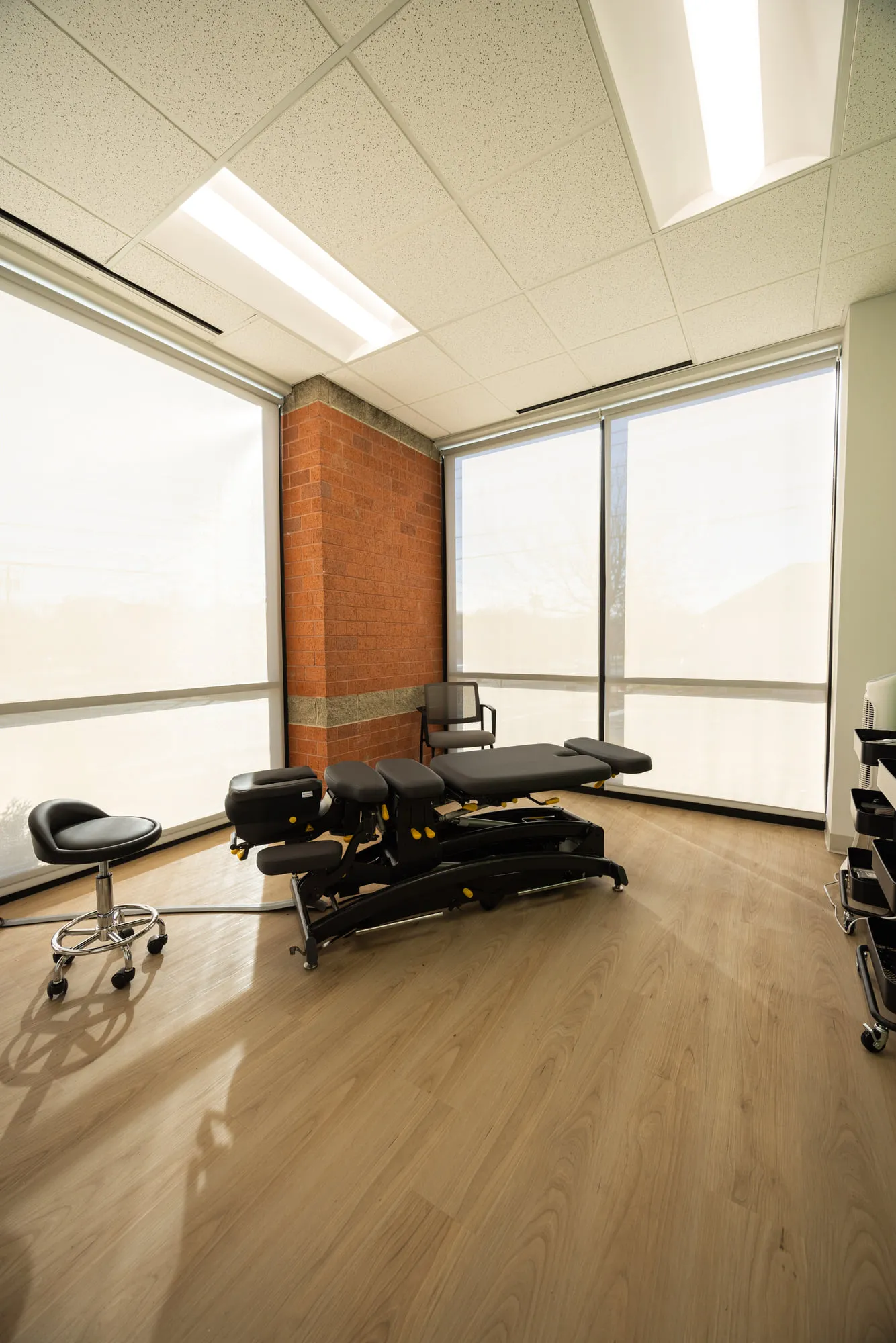 A private treatment room with a chiropractic table and wraparound windows.
