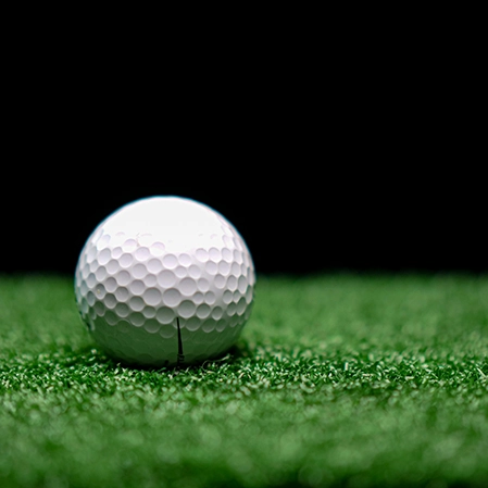 A golf ball sitting on fake grass.